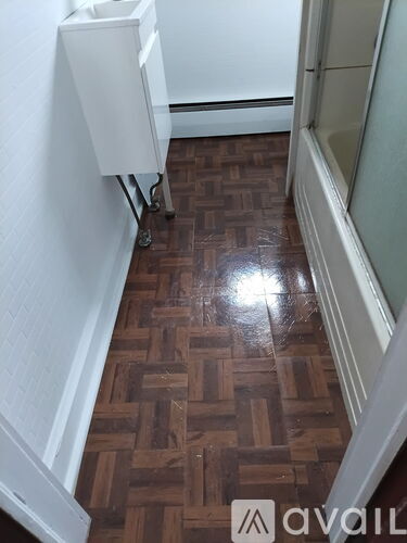 A white sink is on a stand in a room with a wooden floor.