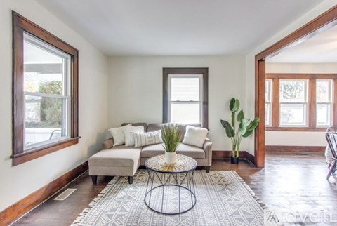A living room with a grey couch and a black and white rug.