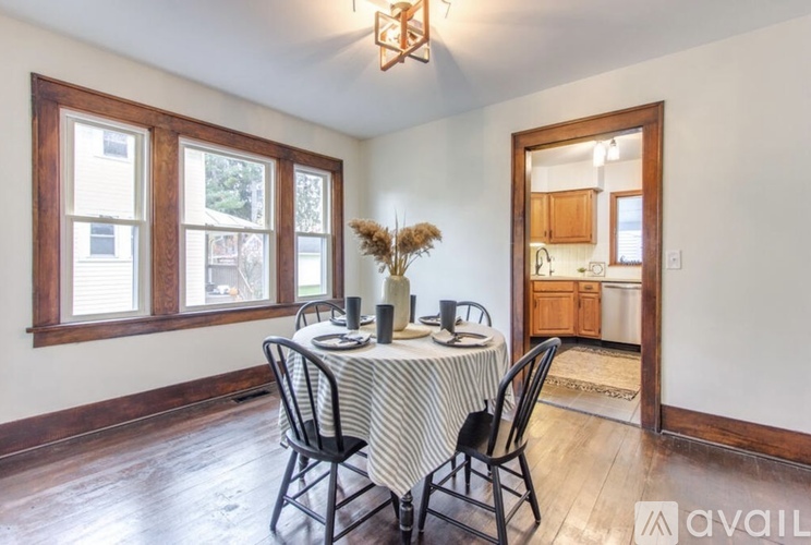 A dining room with a table set for two and a view of the outside through the window.