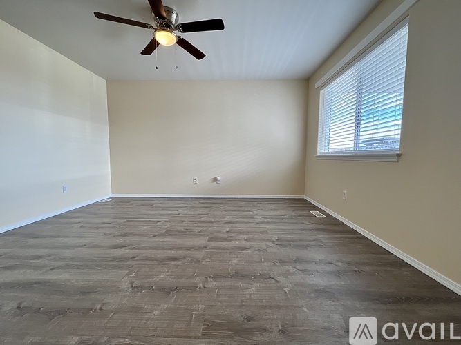 A room with a ceiling fan and a window with blinds.