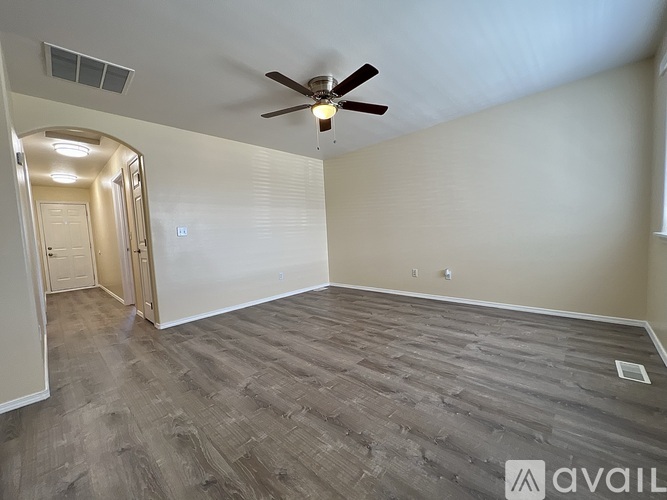 A room with a ceiling fan and light, and a wooden floor.
