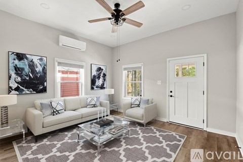 A living room with a white couch, a glass coffee table, and a ceiling fan.