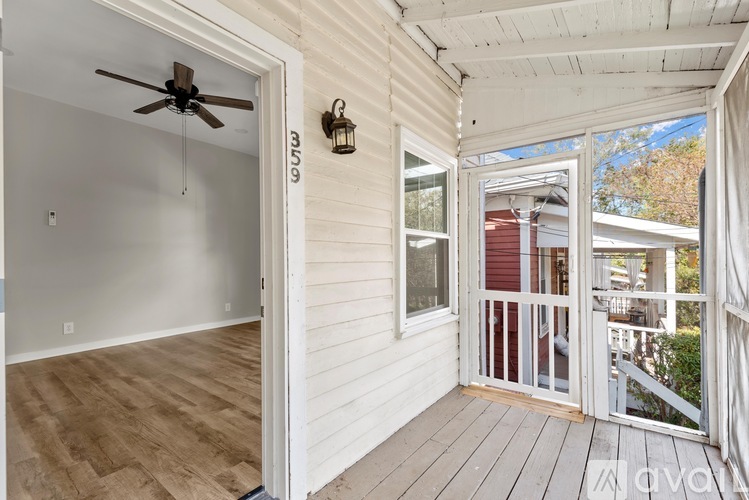 A white room with a ceiling fan and a door leading to a balcony.