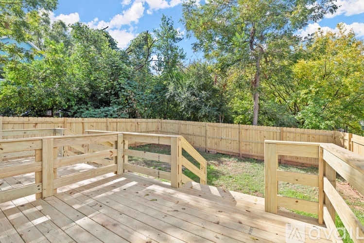 A wooden deck with a railing and steps leading to a grassy area.