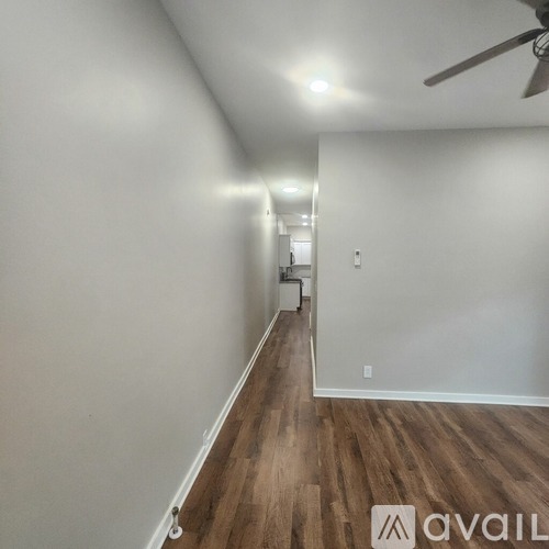 A long hallway with wood floors and a ceiling fan.