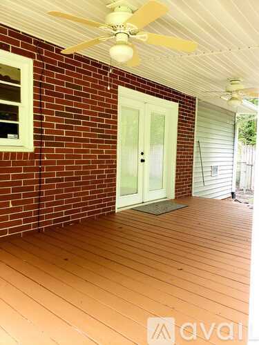 A wooden deck with a ceiling fan and a door.