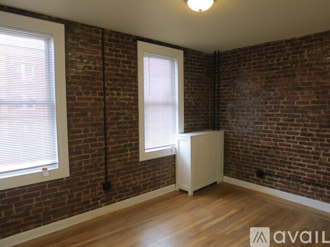 A room with a brick wall and a white radiator.