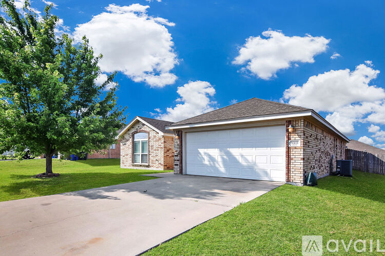 A house with a garage and a tree in front of it.