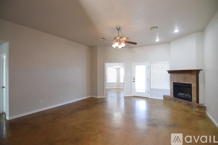 A spacious living room with a fireplace and a ceiling fan.