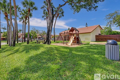 A backyard with a playground and a house in the background.