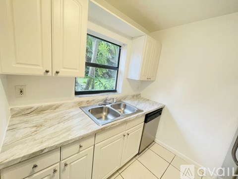 A kitchen with white cabinets and a marble countertop.