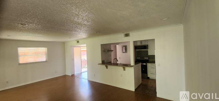 A spacious room with a kitchen area in the background.
