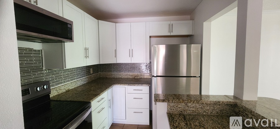 A kitchen with white cabinets and a black countertop.