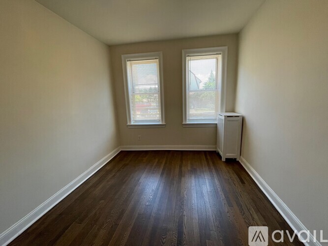 A room with wooden floors and two windows.