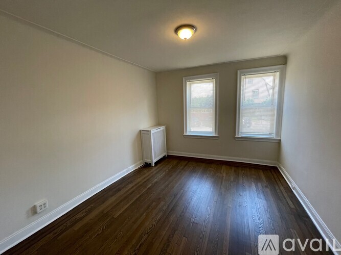 A room with wooden floors and two windows.