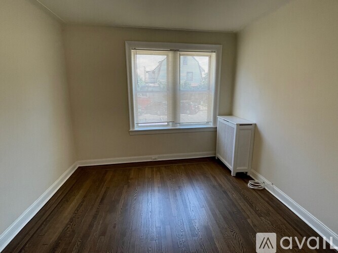 A room with wooden floors and a window with blinds.
