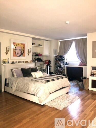 A bedroom with a large bed and a painting of a woman's face on the wall.