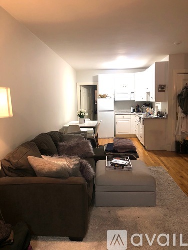 A living room with a couch and a coffee table in front of a kitchen.