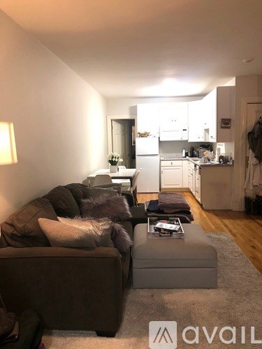 A living room with a couch and a coffee table in front of a kitchen.