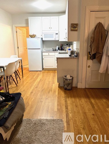 A kitchen with a white fridge and wooden floors.