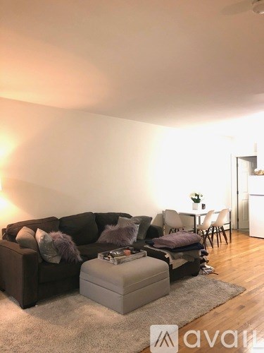 A living room with a couch, ottoman, and chairs.