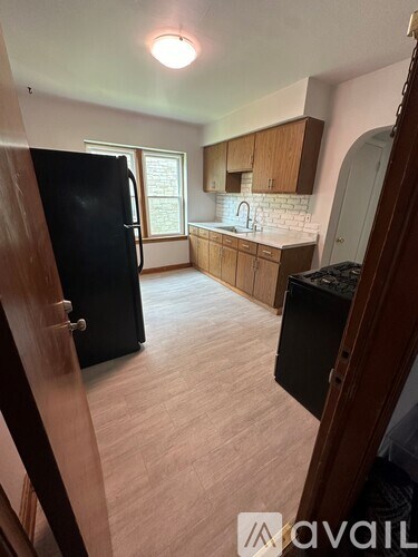 A kitchen with a black refrigerator and wooden cabinets.