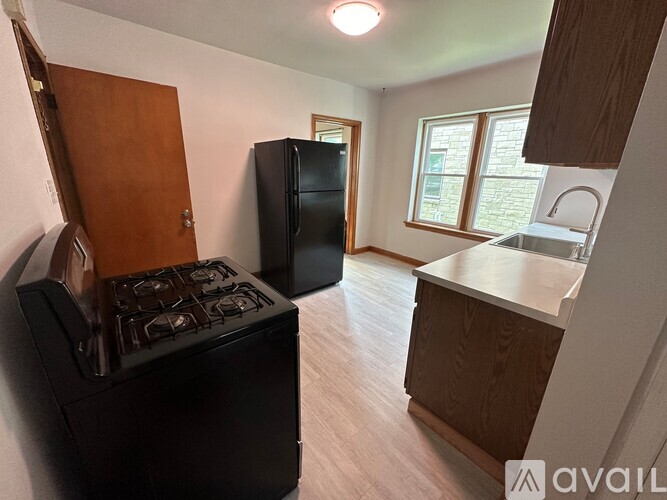 A kitchen with a black stove, black refrigerator, and wooden cabinets.