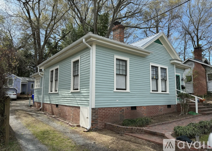 A blue house with a white door and windows is surrounded by trees.