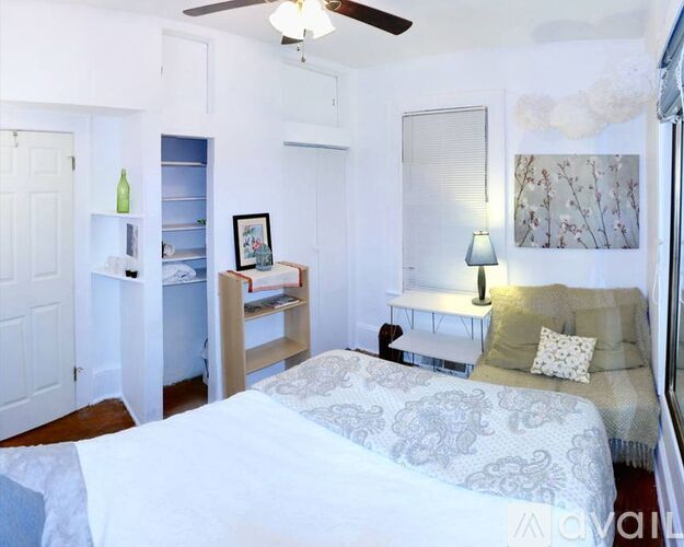 A bedroom with a bed, a bench, and a ceiling fan.