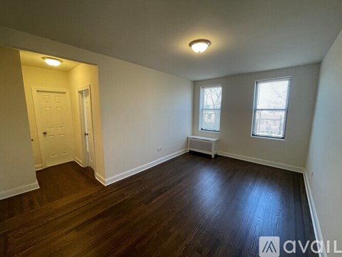 A room with wooden floors and white walls, with a window and a radiator.