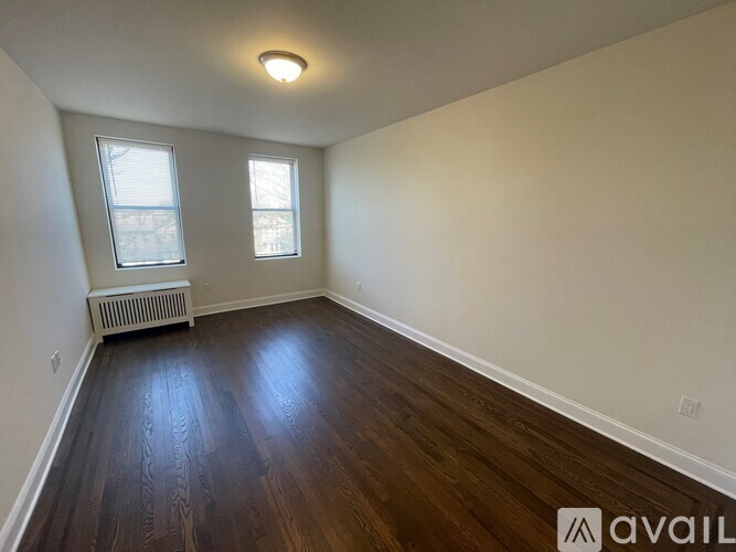 A room with wooden floors and two windows.
