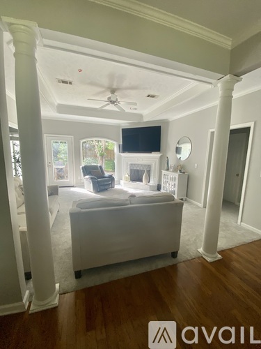 A living room with a white couch and a television on the wall.