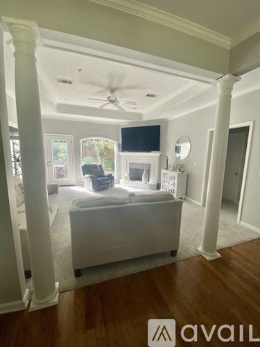 A living room with a white couch and a television on the wall.