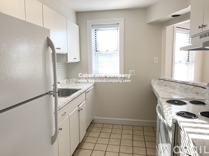 A kitchen with a white refrigerator and a white stove top oven.