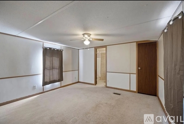 A spacious room with a carpeted floor and a ceiling fan.