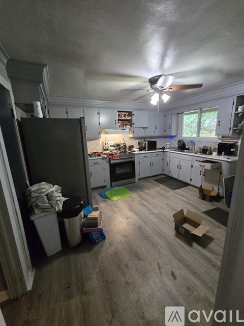 A kitchen with a refrigerator, cabinets, and a ceiling fan.