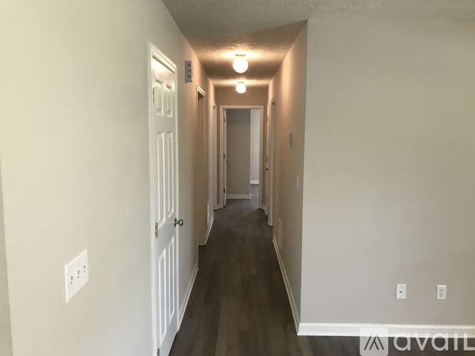 A long hallway with white walls and wood floors.