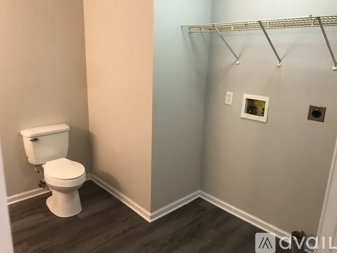 A white toilet sits in a bathroom with a grey wall and a white towel bar.