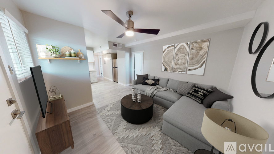A living room with a grey couch and a television on a wooden stand.