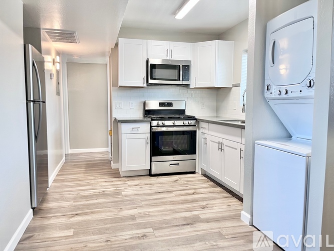 A kitchen with white cabinets and a stainless steel refrigerator.