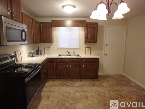 A kitchen with brown cabinets and a black stove top oven.