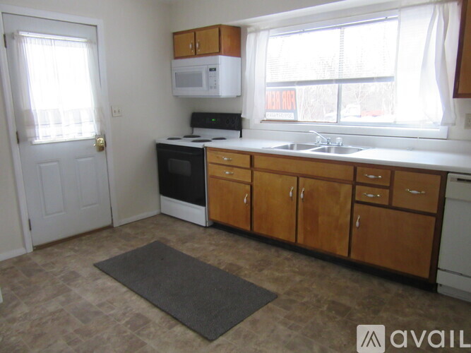 A kitchen with wooden cabinets and a white microwave above the stove.