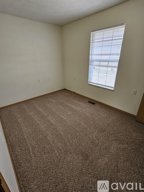 A room with a carpeted floor and a window with blinds.