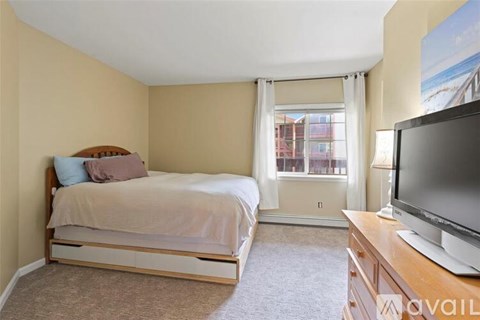 A bedroom with a bed, a television, and a window with curtains.
