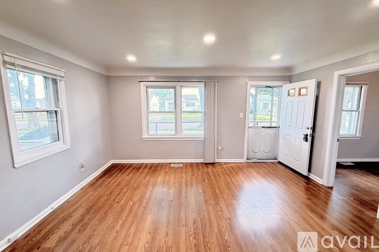 A spacious room with wooden flooring and white walls.
