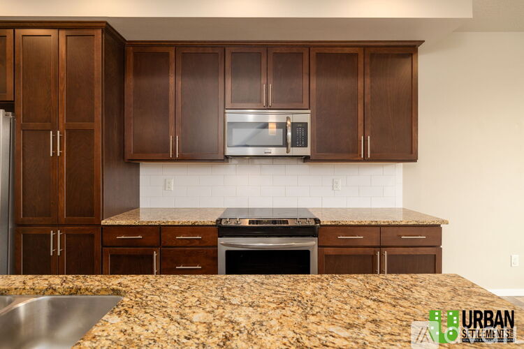 A kitchen with brown cabinets and a granite countertop.