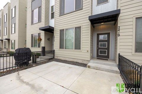 A black grill is on the patio of a beige townhouse.