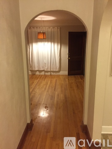 A hallway with a wooden floor and a white curtain.