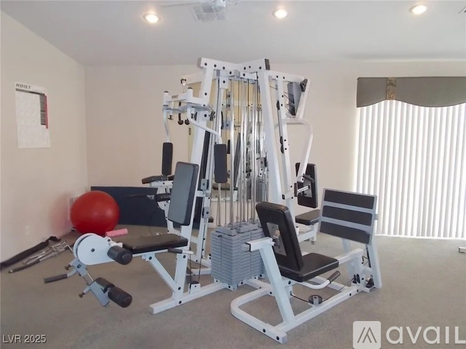 A home gym with a multi-station weight bench and a red exercise ball.
