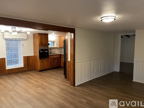 A room with wooden floors and a kitchen area with a stove and cabinets.